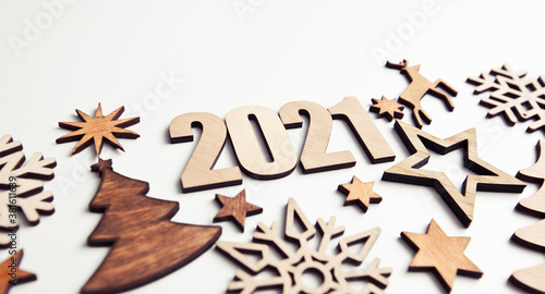 The beautiful christmas background with a lot of small wooden decorations and wooden numbers 2021 on the white desk.