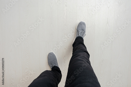 Man will take a step, wooden floor, feet in sneakers, close-up, top view, copy space