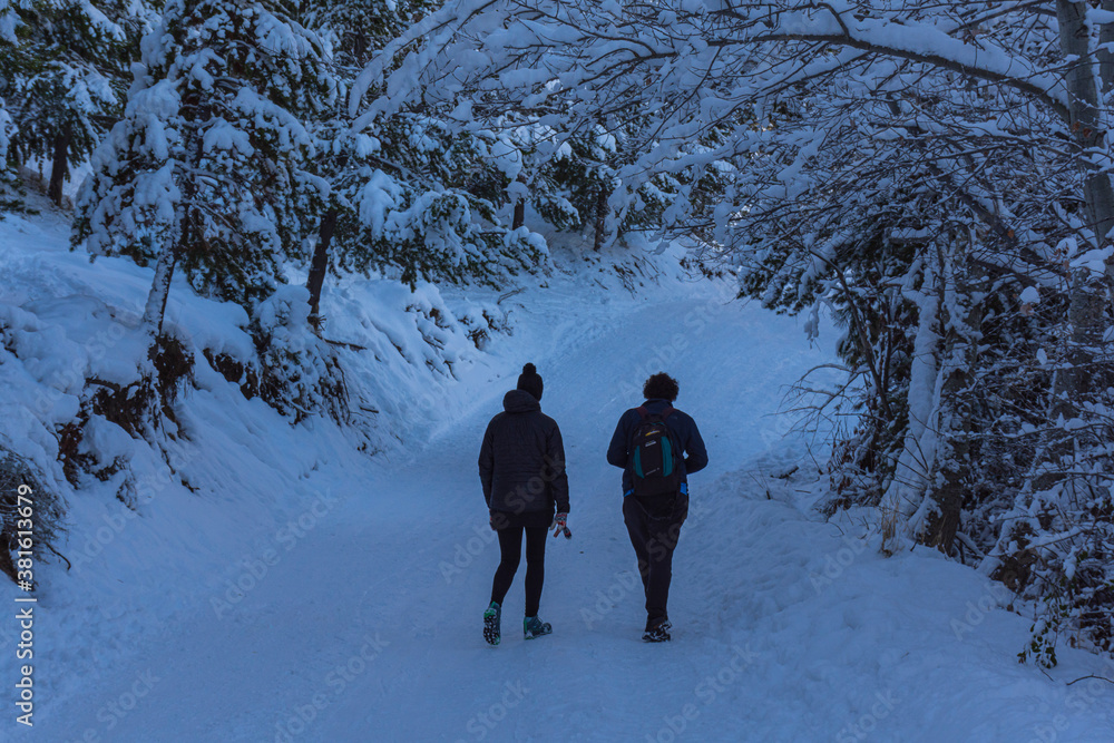 A young couple walking in a snow covered path during winter season in Esquel, Patagonia, Argentina
