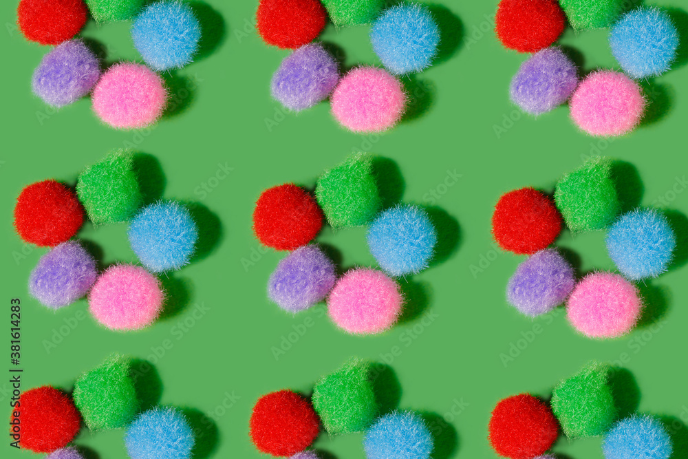 Pattern. Fluffy balls of different colors on a green background. Multicolored balls of thread lie in the shape of a flower. Bright cheerful background. Pattern. Fluffy balls of different colors on a green background. Multicolored balls of thread lie in the shape of a flower. Bright cheerful background.