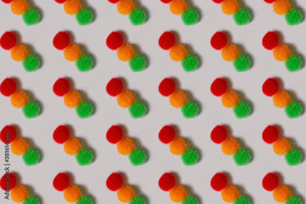 Pattern. Fluffy red, yellow and green balls on a white background. Multi-colored balls of thread lie in rows. Bright cheerful background. Pattern. Fluffy red, yellow and green balls on a white background. Multi-colored balls of thread lie in rows. Bright cheerful background.