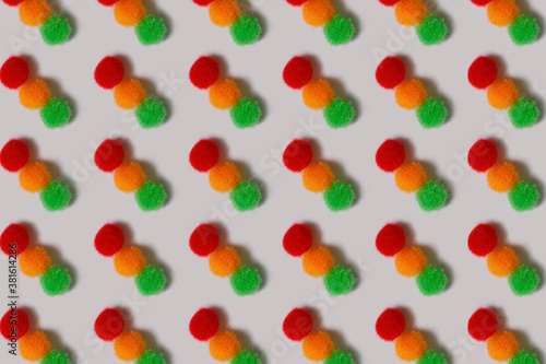 Fototapeta Naklejka Na Ścianę i Meble -  Pattern. Fluffy red, yellow and green balls on a white background. Multi-colored balls of thread lie in rows. Bright cheerful background.