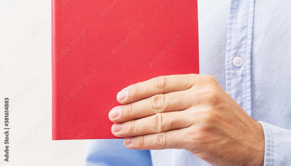 Man's hand with red book, closeup, cropped image, copy space Man's hand with red book, closeup, cropped image, copy space