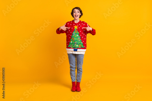 Full length photo of shocked crazy girl point finger christmas tree decor pullover x-mas gift granny present surprise theme party wear denim boots isolated bright shine color background