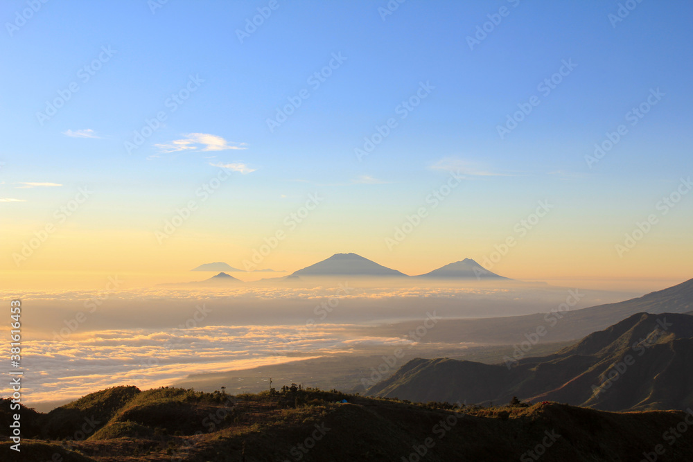 Golden sunrise on Mount Prau. We can see the Sindoro and Sumbing mountains with a sea of clouds. Mount Prau, Central Java, Indonesia.