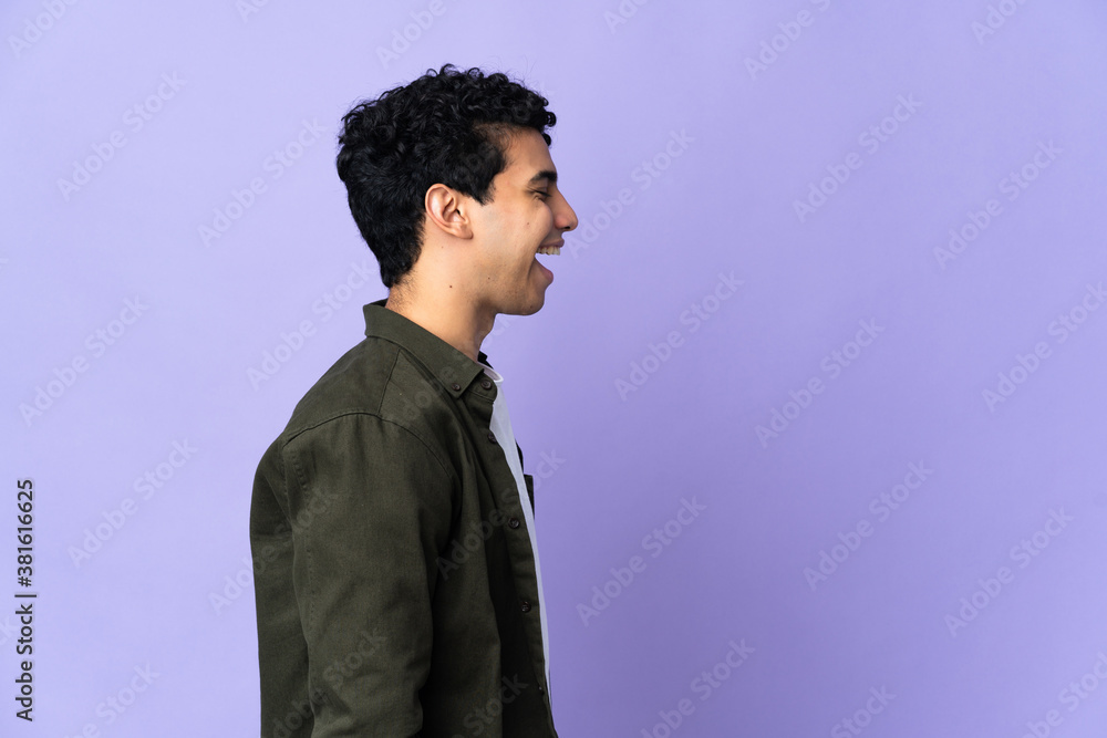 Obraz premium Young Venezuelan man isolated on purple background laughing in lateral position