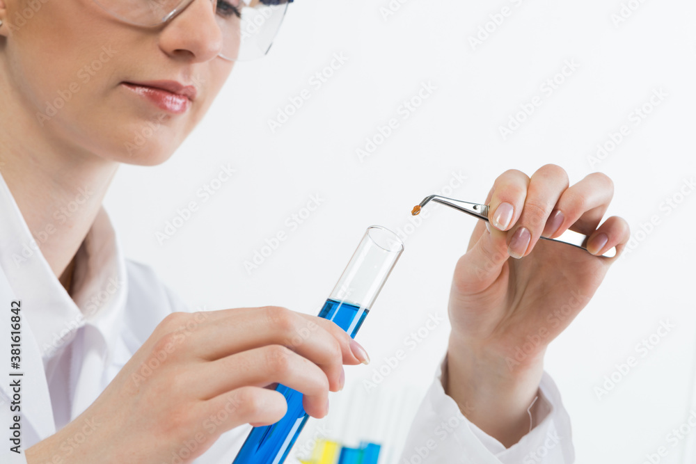 Scientist puts sample into test tube with liquid Scientist puts sample into test tube with liquid