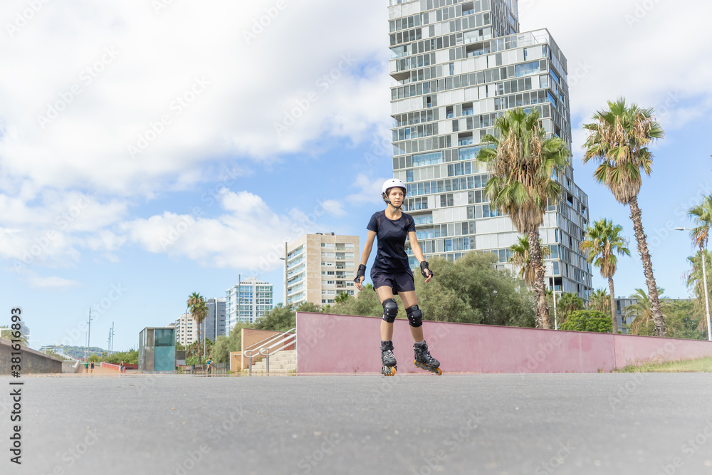 Young roller skater caucasian woman in the white helmet and black sporty clothes, cloudy day, skatepark, urban environment. Young roller skater caucasian woman in the white helmet and black sporty clothes, cloudy day, skatepark, urban environment.