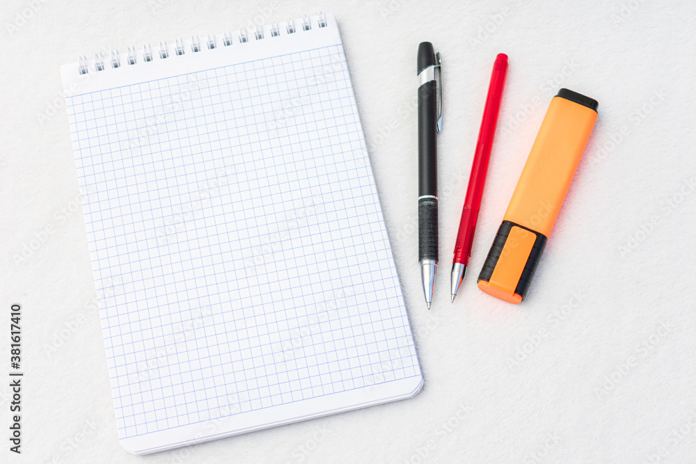 Notebook, pens and marker, top view, white background, copy space Notebook, pens and marker, top view, white background, copy space