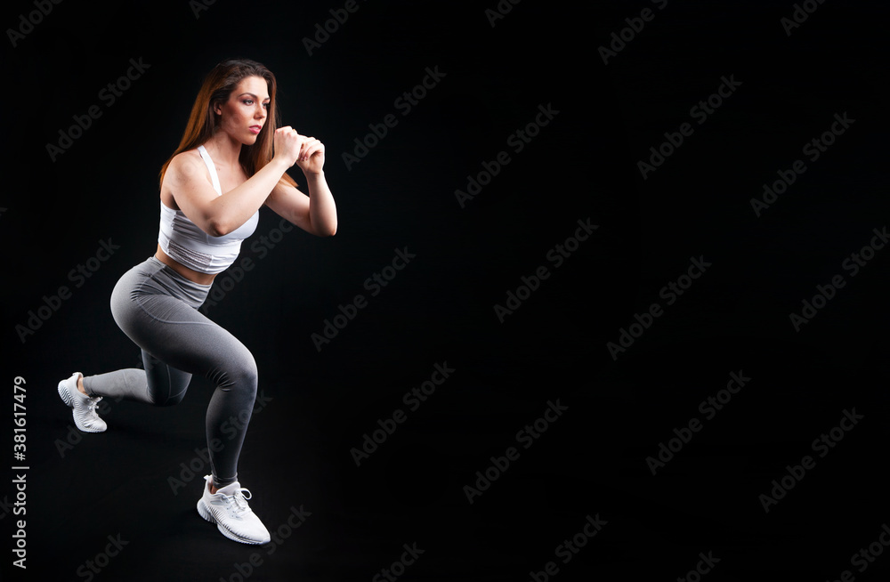 woman athlete in sportswear posing in studio on black background