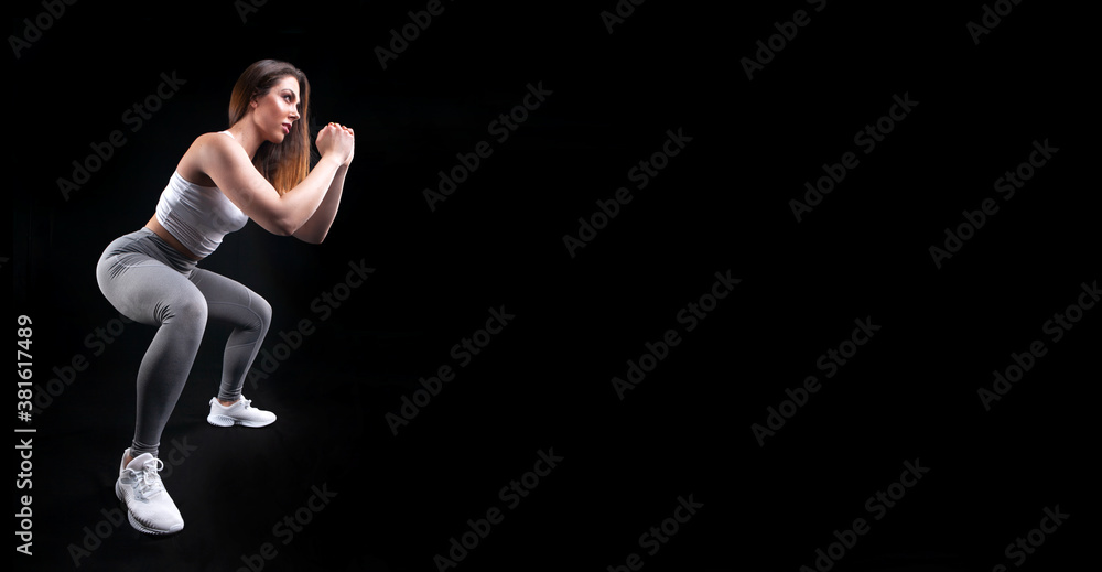woman athlete in sportswear posing in studio on black background