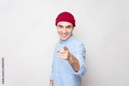 Young man points at you, copying the space, portrait, white background photo