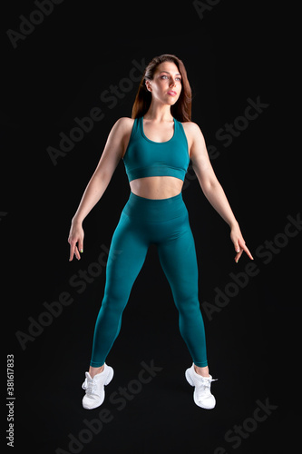woman athlete in sportswear posing in studio on black background