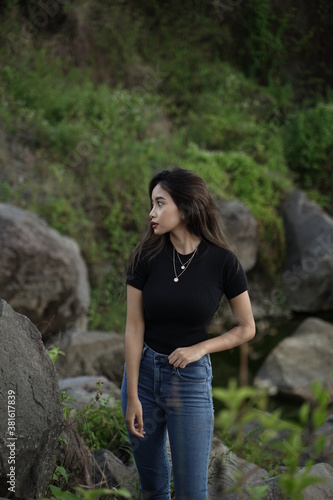 Stylish blonde girl wearing a black shirt with views of natural rocks, lake water and clear sky. female t-shirt models for mockups and templates.