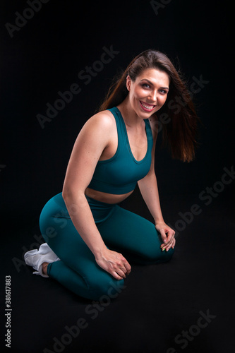 woman athlete in sportswear posing in studio on black background © Yehor Serdiuk