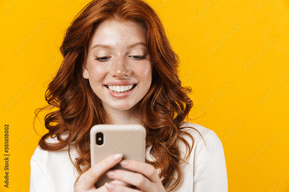 Image of ginger happy girl smiling and using mobile phone Image of ginger happy girl smiling and using mobile phone