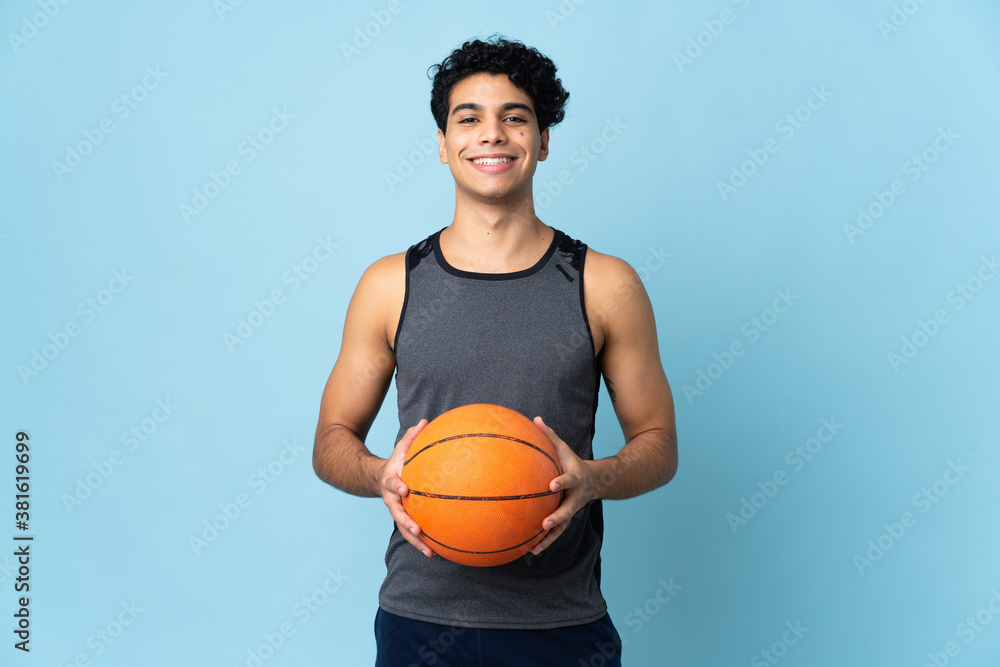 Young Venezuelan man isolated on blue background playing basketball - obrazy, fototapety, plakaty 