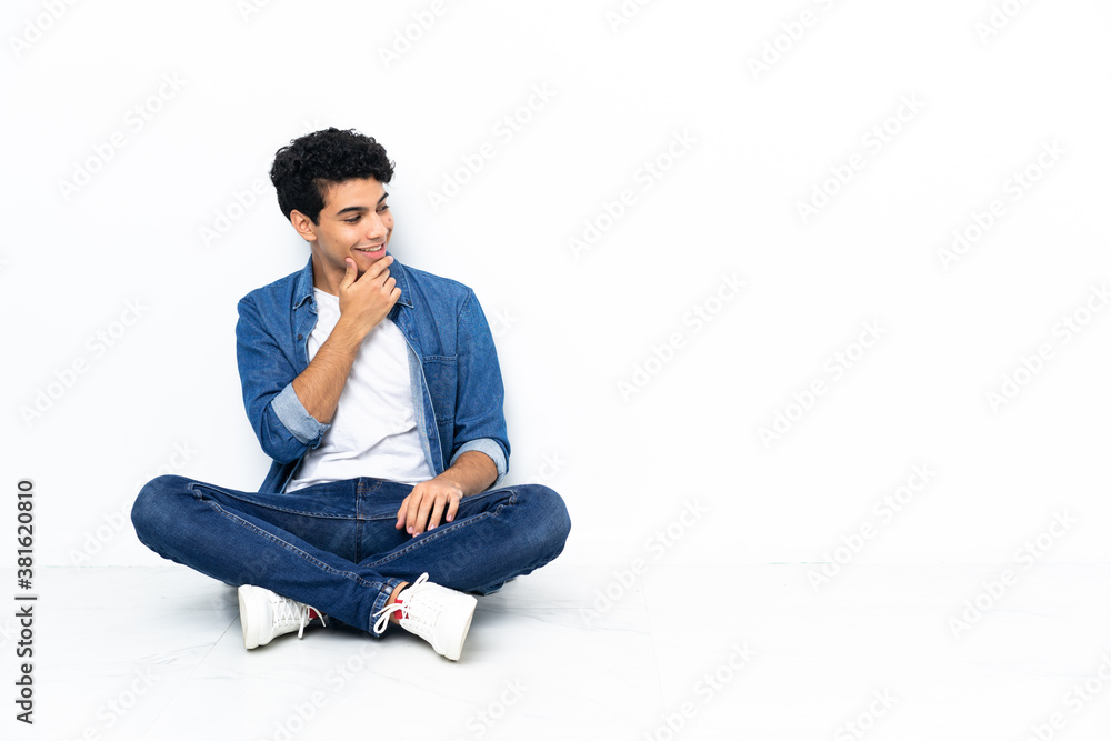 Venezuelan man sitting on the floor looking to the side Venezuelan man sitting on the floor looking to the side