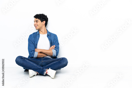 Venezuelan man sitting on the floor with arms crossed and happy © luismolinero