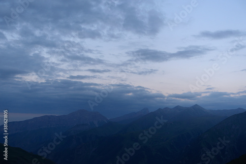 Fototapeta Naklejka Na Ścianę i Meble -  Silhouettes of mountains in the evening haze. Mountain ranges at sunset. Dusk.
