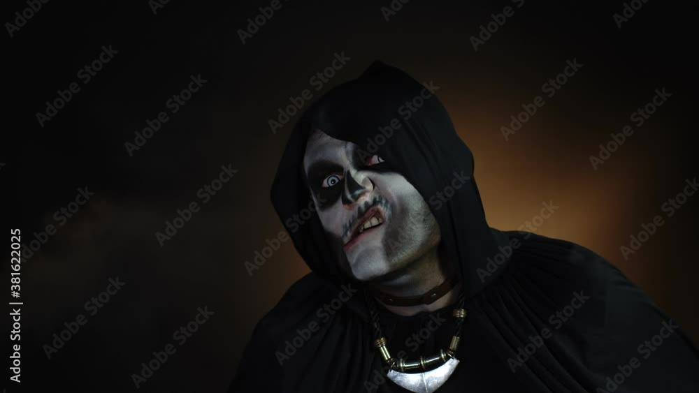 Creepy, crazy man with skeleton makeup in hood making angry faces, shaking head, trying to scare Creepy, crazy man with skeleton makeup in hood making angry faces, shaking head, trying to scare