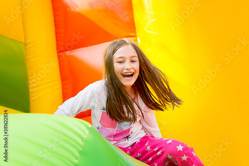 Happy little girl having lots of fun on a jumping castle during sliding Fototapeta