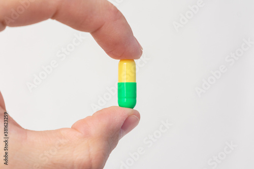 Person holding a medical capsule, fingers, close-up, cropped image, copy space