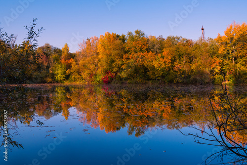 Colorful autumnal photo of a small lake  autumnal small lake with colorful trees in the background  reflections