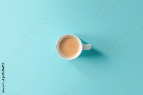 Coffee cup on blue background, top view