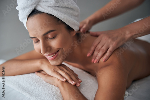 Professional masseuse massaging female back in spa salon