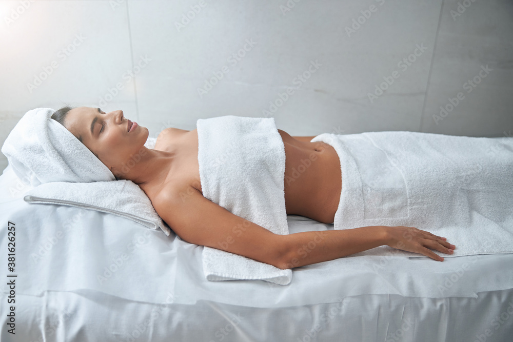 Beautiful young woman lying on massage table in spa salon Beautiful young woman lying on massage table in spa salon