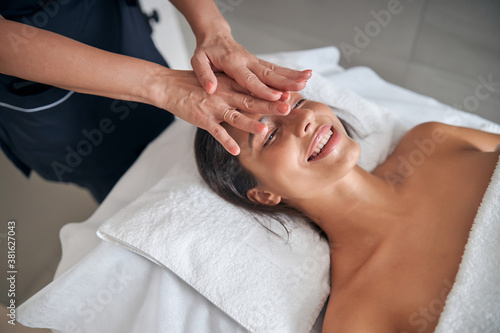 Masseur hands massaging female face in spa salon