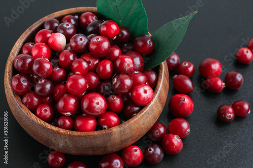Cranberries in wooden bowl on black background. Nature, autumn, crop, food, berry concept.