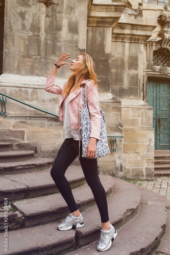 young beautiful woman traveling in europe, summer vacation, leather pink jacket, glam rock style, flirty, city street style