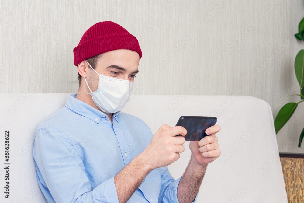 Person in a medical mask playing mobile games, portrait