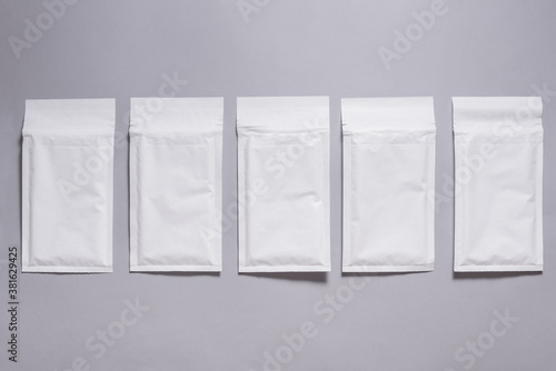 Lot of white paper bubble envelopes on grey background, textured background