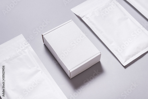 Lot of white paper bubble envelopes and carton box on grey background, textured background