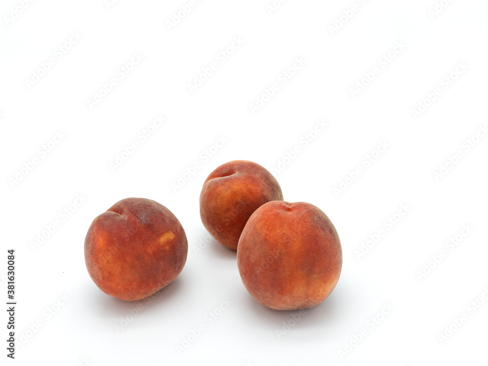 Three ripe whole pink peaches isolated on white background. Located in the lower left corner. Three ripe whole pink peaches isolated on white background. Located in the lower left corner.