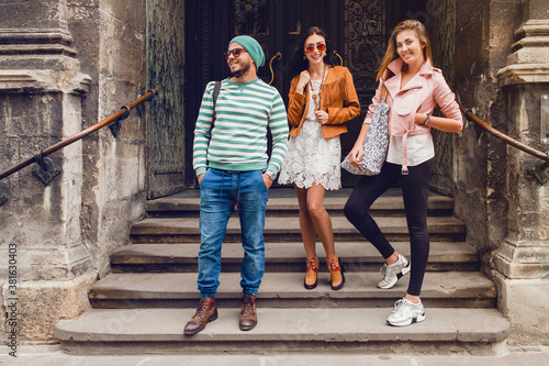young hipster company of friends traveling, vintage style, europe vacation, sunglasses, old city center, happy positive mood, smiling, embracing, pointing finger, looking forward