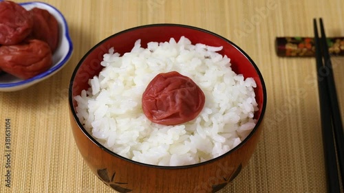 Bowl with rice and traditional Japanese umeboshi close up photo