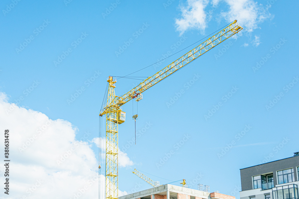 Construction of an apartment building, building cranes, blue sky with clouds, toned Construction of an apartment building, building cranes, blue sky with clouds, toned