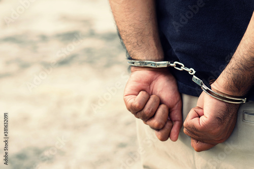 Arrest the offender. Prison male criminal standing in handcuffs with hands behind back.  © methaphum