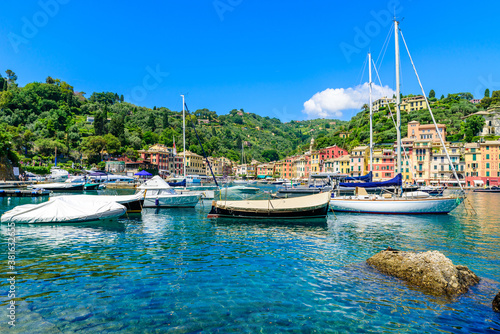 Portofino, Italy - Harbor town with colorful houses and yacht in little bay. Liguria, Genoa province, Italy. Italian fishing village with beautiful sea coast landscape in summer season. © Simon Dannhauer