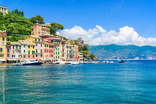 Portofino, Italy - Harbor town with colorful houses and yacht in little bay. Liguria, Genoa province, Italy. Italian fishing village with beautiful sea coast landscape in summer season. © Simon Dannhauer