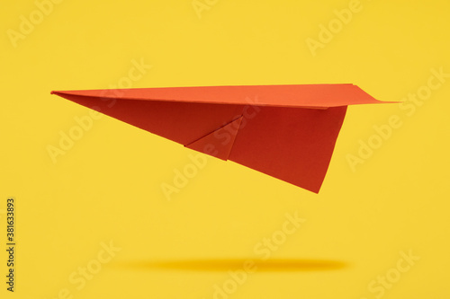 Red paper aircraft fly over yellow background photo