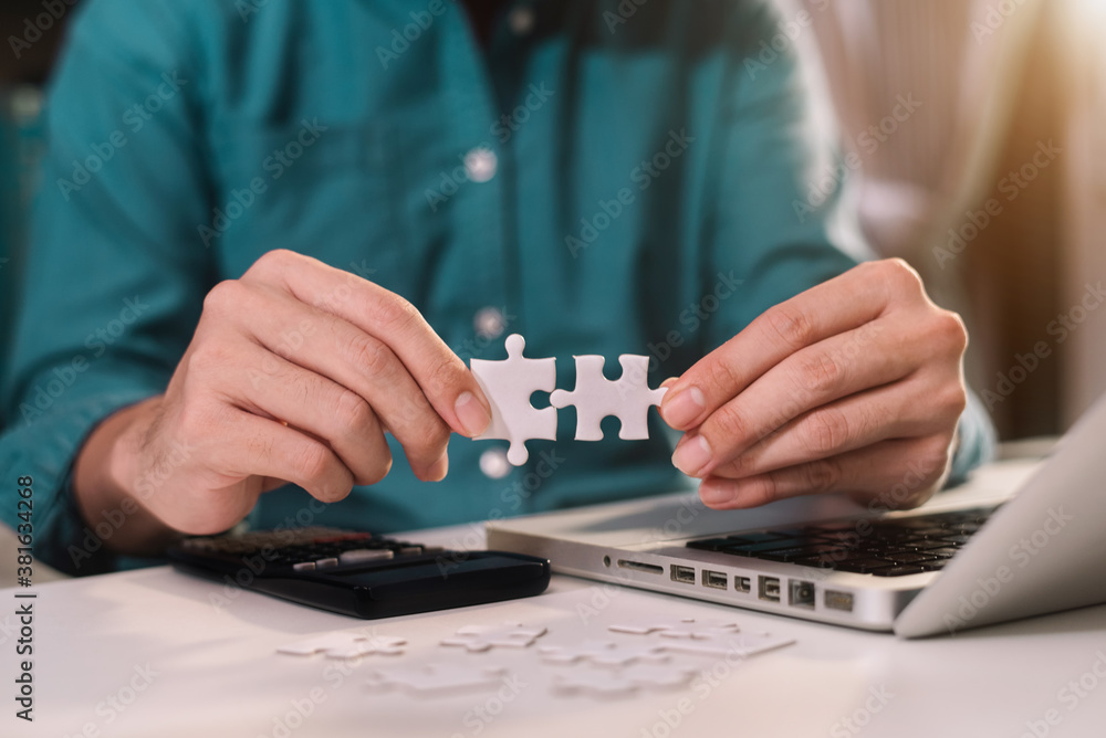 Businessman hand connecting jigsaw puzzle with calculator at office. Businessman hand connecting jigsaw puzzle with calculator at office.