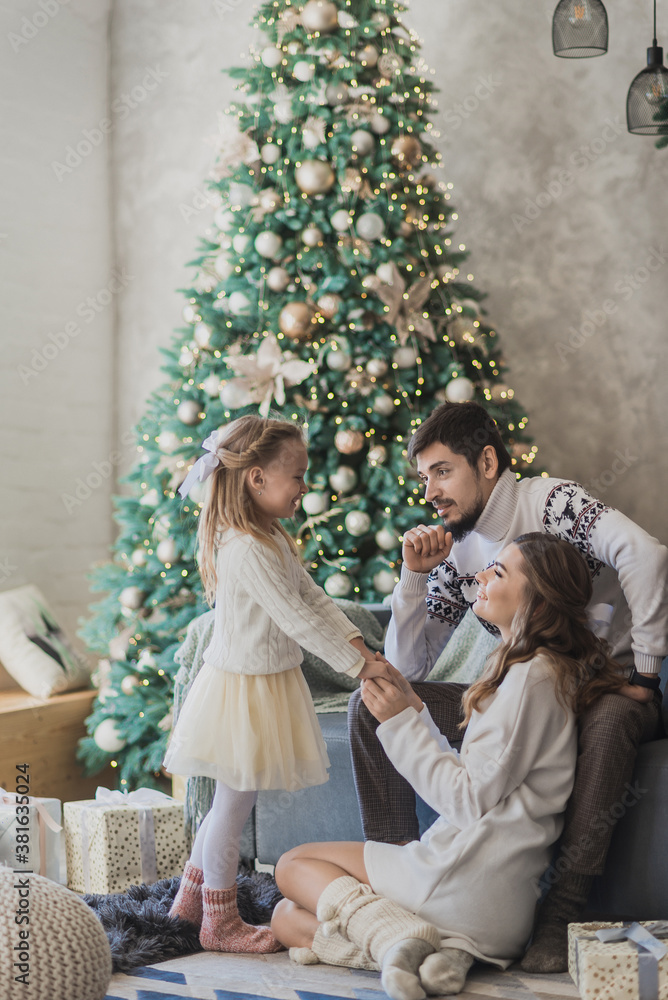 Happy family in christmas decorations. Mother father and little daughter in day time cozy christmas atmosphere Happy family in christmas decorations. Mother father and little daughter in day time cozy christmas atmosphere