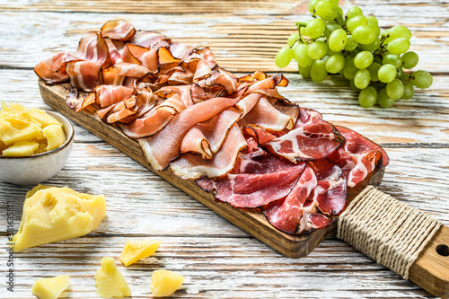 Set of cold cured italian meat Ham, prosciutto, pancetta, bacon. White wooden background. Top view