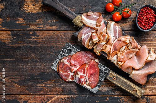 Set of cold cured italian meat Ham, prosciutto, pancetta, bacon. Dark wooden background. Top view. Copy space