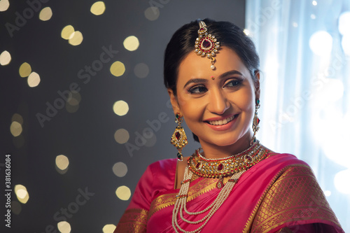 Woman in a pink saree looking sideways with a smile on her face	 photo